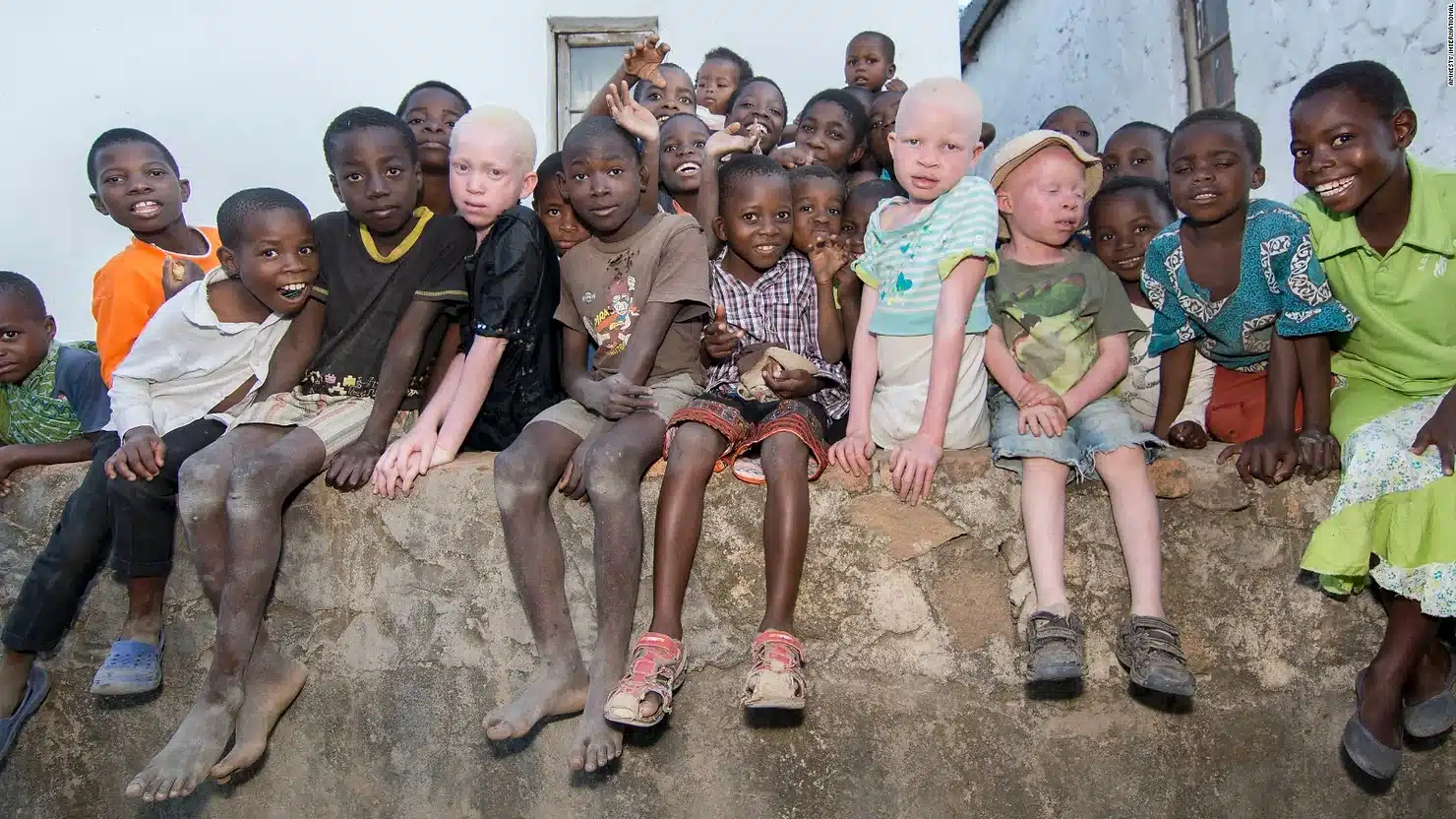 iyang Lots of African children sitting on a wall.